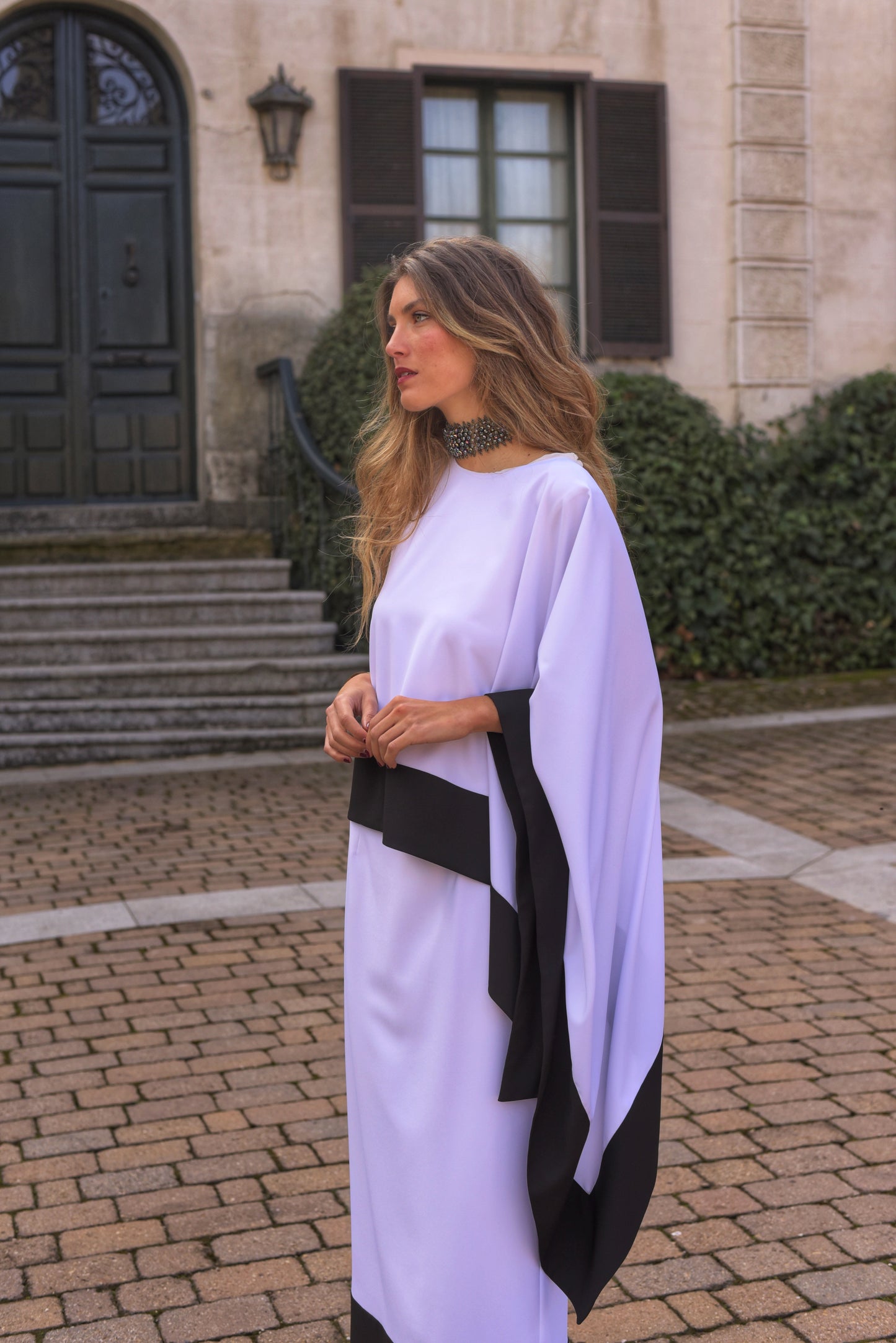 Conjunto de Fiesta midi, blusa asimétrica cuello a caja con manga capote y falda recta, tejido crepe color blanco con zócalo negro.