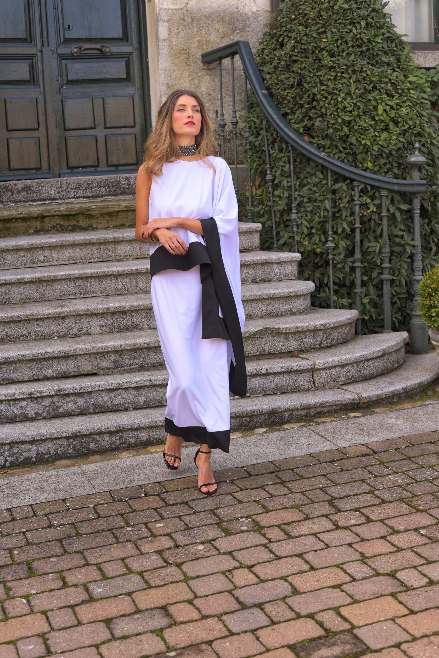 Conjunto de Fiesta midi, blusa asimétrica cuello a caja con manga capote y falda recta, tejido crepe color blanco con zócalo negro.