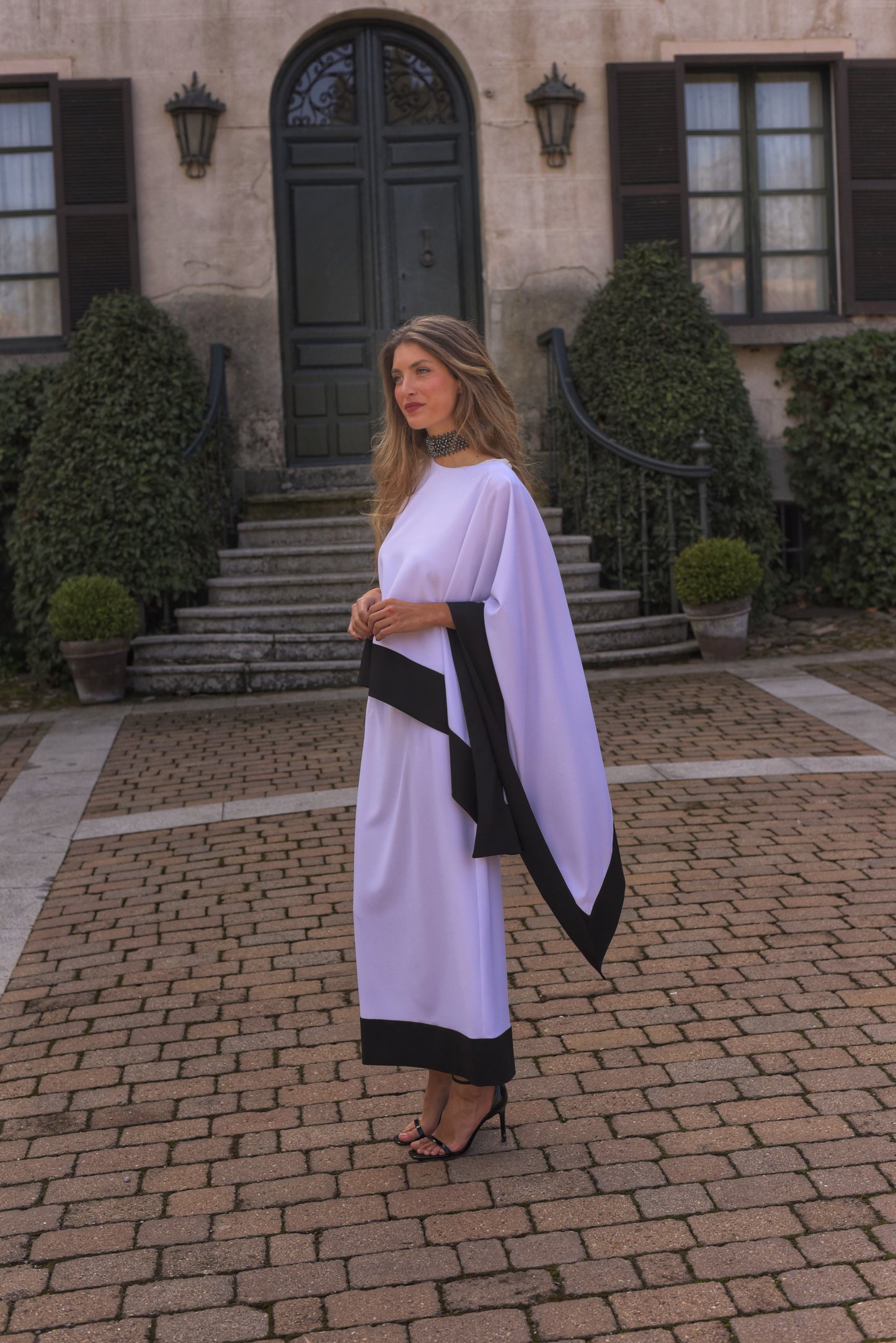 Conjunto de Fiesta midi, blusa asimétrica cuello a caja con manga capote y falda recta, tejido crepe color blanco con zócalo negro.