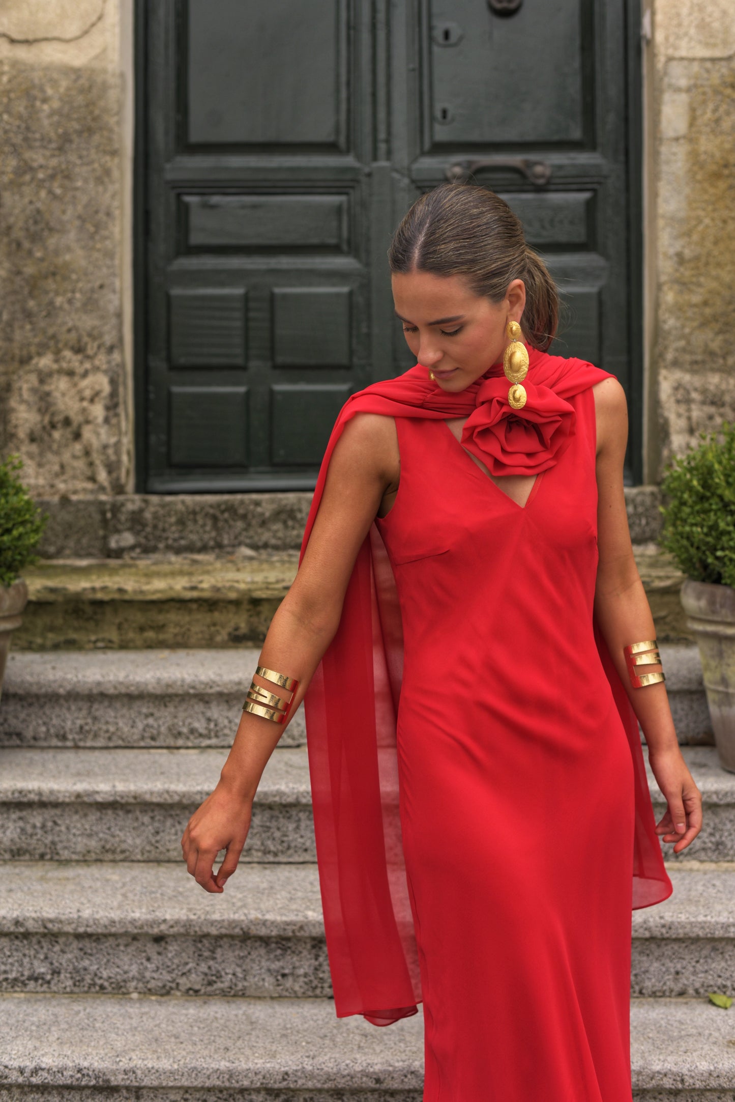 El Vestido Lady Gacela rojo es una propuesta delicada y femenina para invitadas que buscan un estilo fluido con toques sofisticados. De corte lencero, este vestido largo de fiesta presenta un elegante escote en pico tanto en el delantero como en la espalda, realzando sutilmente la silueta.
Está confeccionado en gasa ligera de tono rojo vibrante y se completa con una capita vaporosa y un broche de flor multiposición que puedes colocar en el escote central o lateral, permitiendo adaptar el look según la ocas