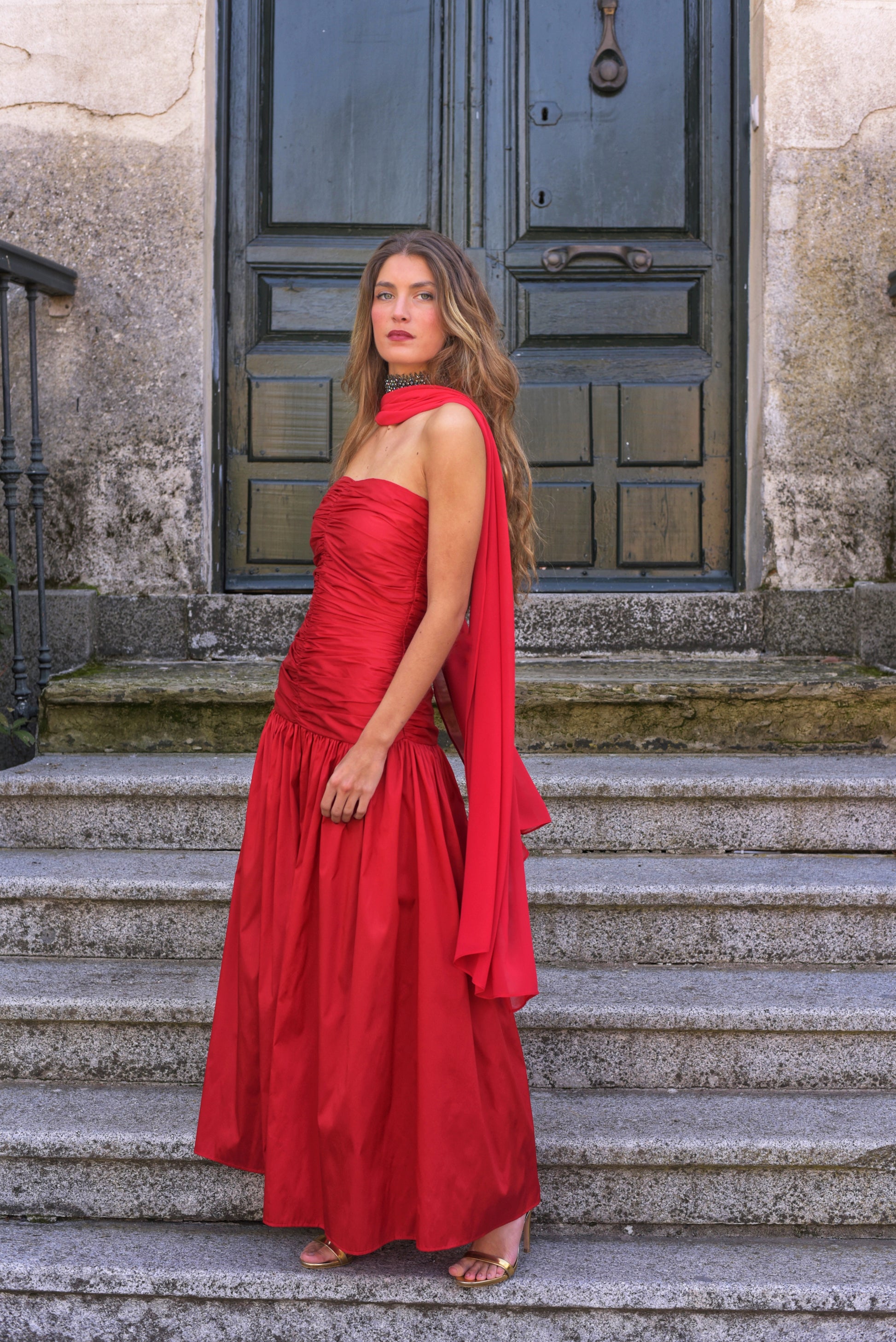 El Vestido Lady Pantera rojo es una elección atrevida y elegante para invitadas que buscan un look con presencia y movimiento. Diseñado con un escote palabra de honor y un cuerpo muy fruncido que realza el busto y la figura, este vestido largo de fiesta destaca por su falda abullonada desde la cadera, que aporta volumen y dramatismo con cada paso.

Confeccionado en tafeta de alta calidad en un impactante tono cardenal, incluye un fular de gasa a juego, perfecto para cubrir los hombros con ligereza o jugar c