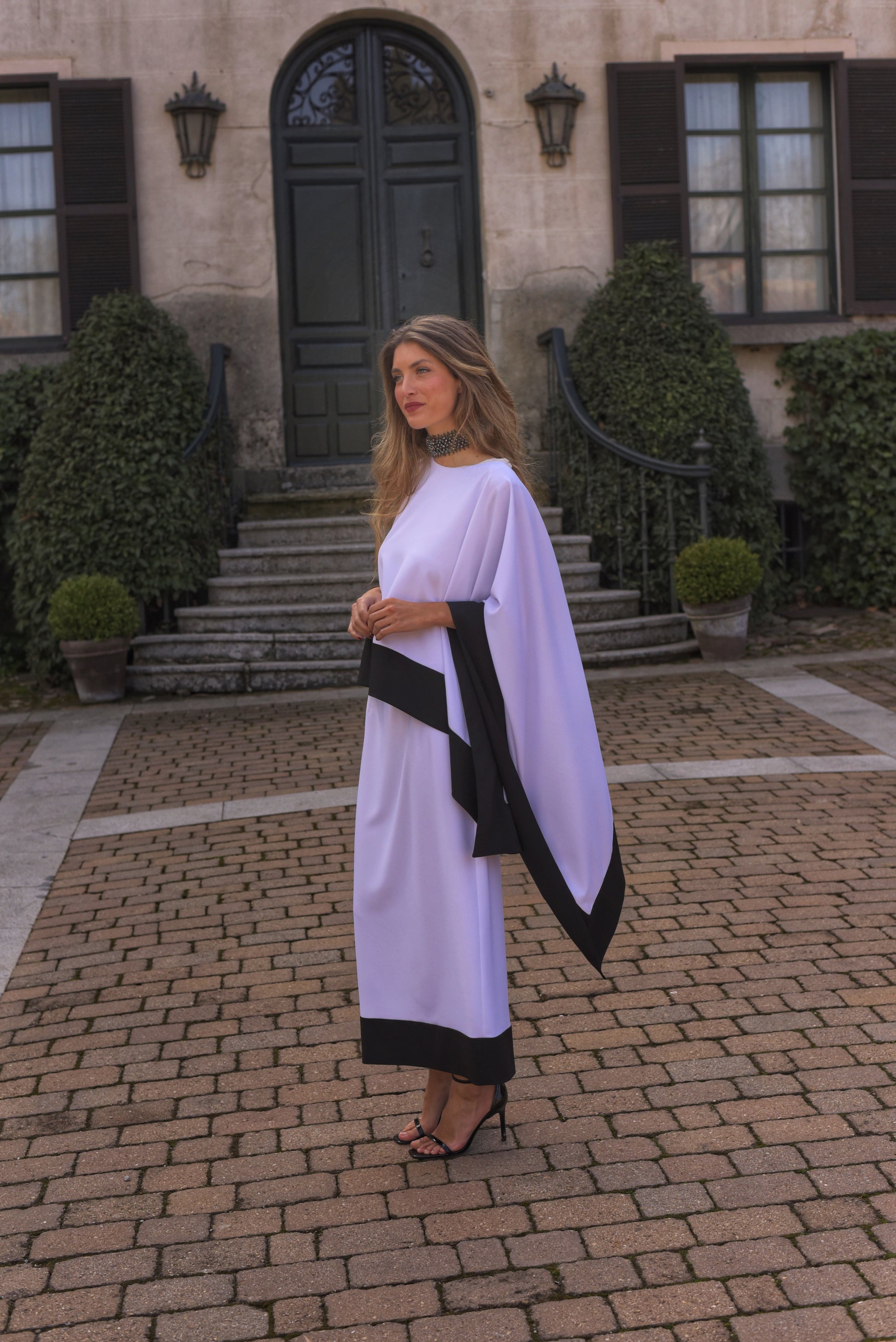 Conjunto de Fiesta midi, blusa asimétrica cuello a caja con manga capote y falda recta, tejido crepe color blanco con zócalo negro. 